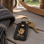 Black Mom memorial keychain with gold lettering resting on a folded handwritten recipe card