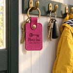 Bright pink Mom's taxi ON DUTY keychain on car keys beside a soccer ball on a car seat