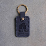 Blueberry navy leather keychain debossed with a gabled house above Mr & Mrs and HOME SWEET HOME, on gray concrete