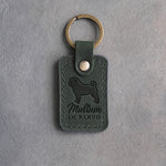 Forest green leather keychain debossed with a pug silhouette and the words Multum IN PARVO, on gray concrete