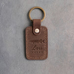 Sicilian Brown leather keychain debossed with a musky above Lars and MUSKY, on gray plaster