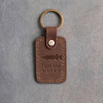 Sicilian Brown leather keychain debossed with a musky above Tight lines and MUSKY, on gray concrete
