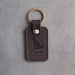 Dark espresso leather keychain debossed with a dog looking up above Pepper and MY CO-PILOT, on gray concrete