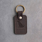Dark espresso leather keychain debossed with a dog looking up above MY CO-PILOT, on gray concrete