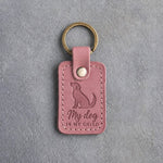 Parisian Blossom pink leather keychain debossed with a mutt looking up above My dog and IS MY CHILD, on gray concrete