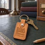Tan Eleanor's LIBRARY keychain hanging from a key in the lock of a glass-fronted bookcase