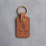 Caramel leather keychain debossed with a single acorn above New dad and EST 2026