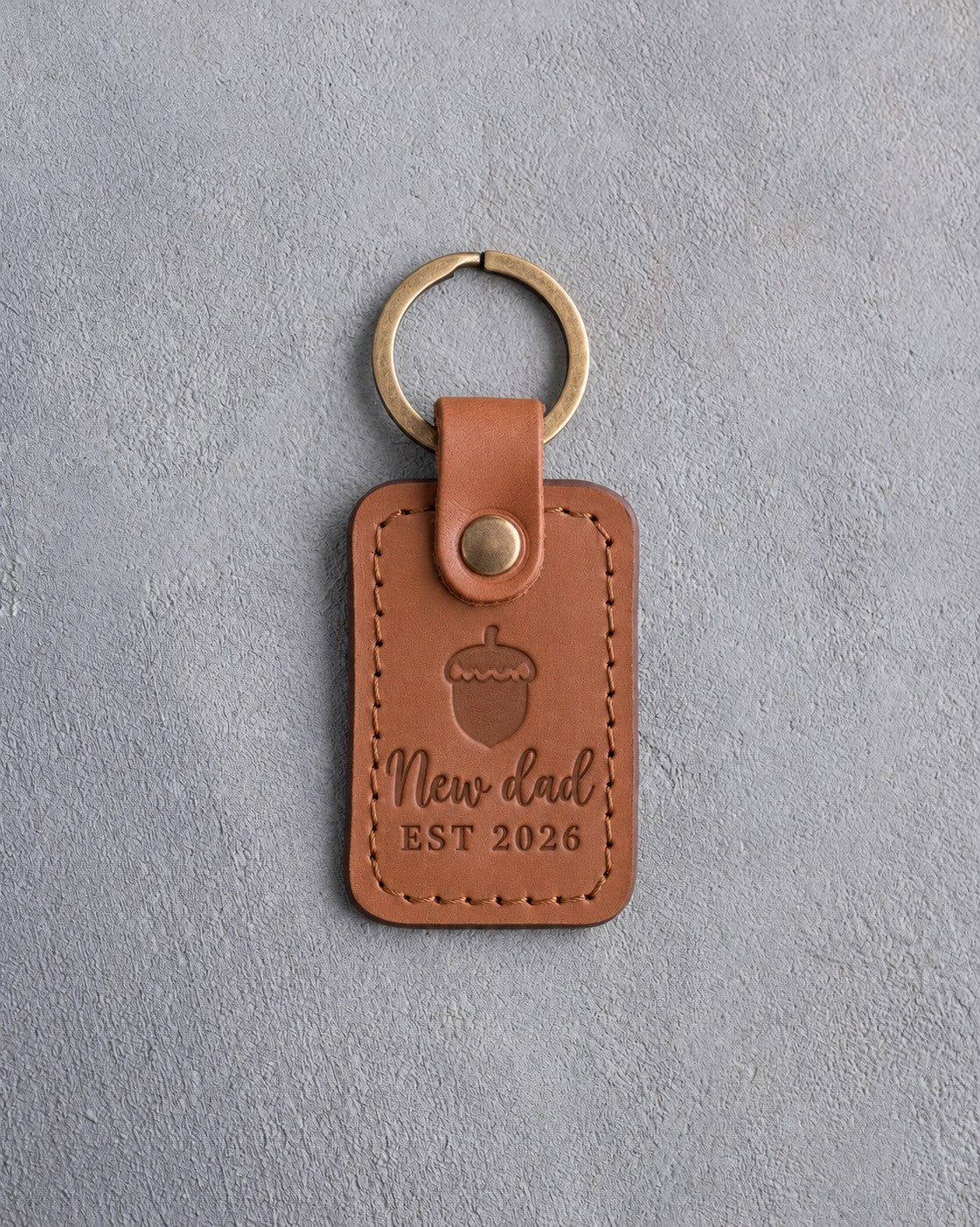 Caramel leather keychain debossed with a single acorn above New dad and EST 2026