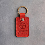 Poppy red leather keychain debossed with a steering wheel above New driver and SINCE 2026