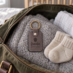 Gray Grandpa EST 2026 keychain lifted from a small gift box on a dining table