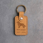 Indian Summer tan leather keychain debossed with a golden retriever above New puppy and EST · 2026, on gray concrete