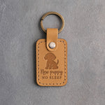 Indian Summer tan leather keychain debossed with a sitting puppy and the words New puppy NO SLEEP, on gray concrete