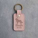 Blush pink leather keychain with a debossed Newfoundland and the words Newfie MOM, on gray concrete
