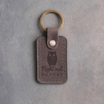Country gray leather keychain debossed with a perched owl above Night owl and READER, on gray concrete