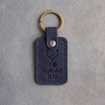 Blueberry navy leather keychain debossed with a stethoscope above the words Night shift and RN, on gray plaster