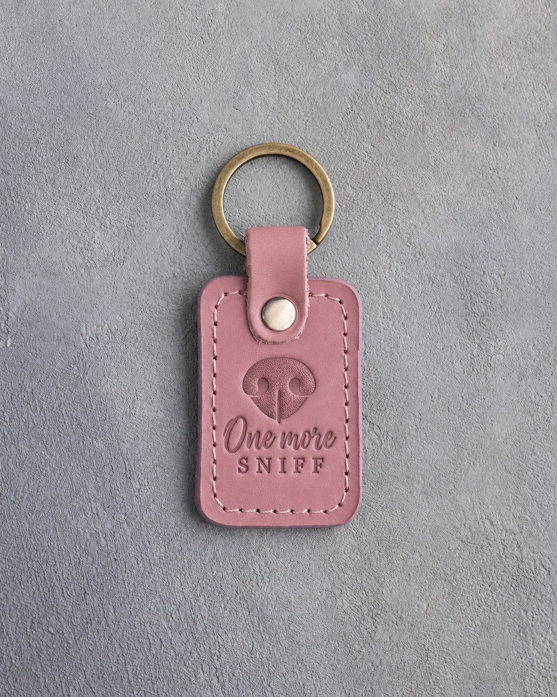 Parisian Blossom pink leather keychain debossed with a dog nose print and the words One more SNIFF, on gray concrete