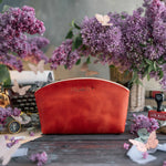 Poppy red leather makeup bag with a personalized gold name, lilacs behind