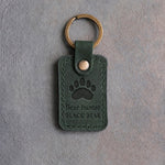 Forest green leather keychain debossed with a black bear paw track above the words Bear hunter and BLACK BEAR, on gray concrete