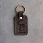Dark espresso leather keychain debossed with a whitetail buck above the name Levi and BOWHUNTER, on gray plaster