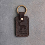 Dark espresso leather keychain debossed with a whitetail buck above the words Whitetail and BOWHUNTER, on gray concrete