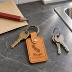 Maya California keychain in golden tan leather clipped to a beach tote on a sunny boardwalk bench
