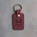Sangria red leather keychain debossed with a small cat beside a Christmas tree above the name Mochi's and 1ST CHRISTMAS