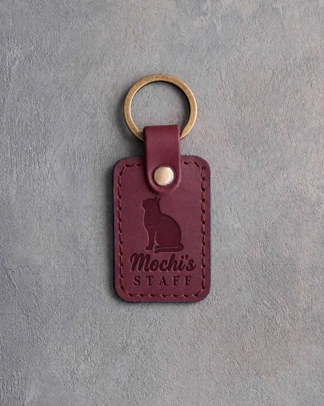 Sangria red leather keychain debossed with a cat looking up above the name Mochi's and the word STAFF