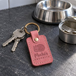 Mochi's FAVORITE keychain in rose pink leather on a knitted throw draped over a sofa