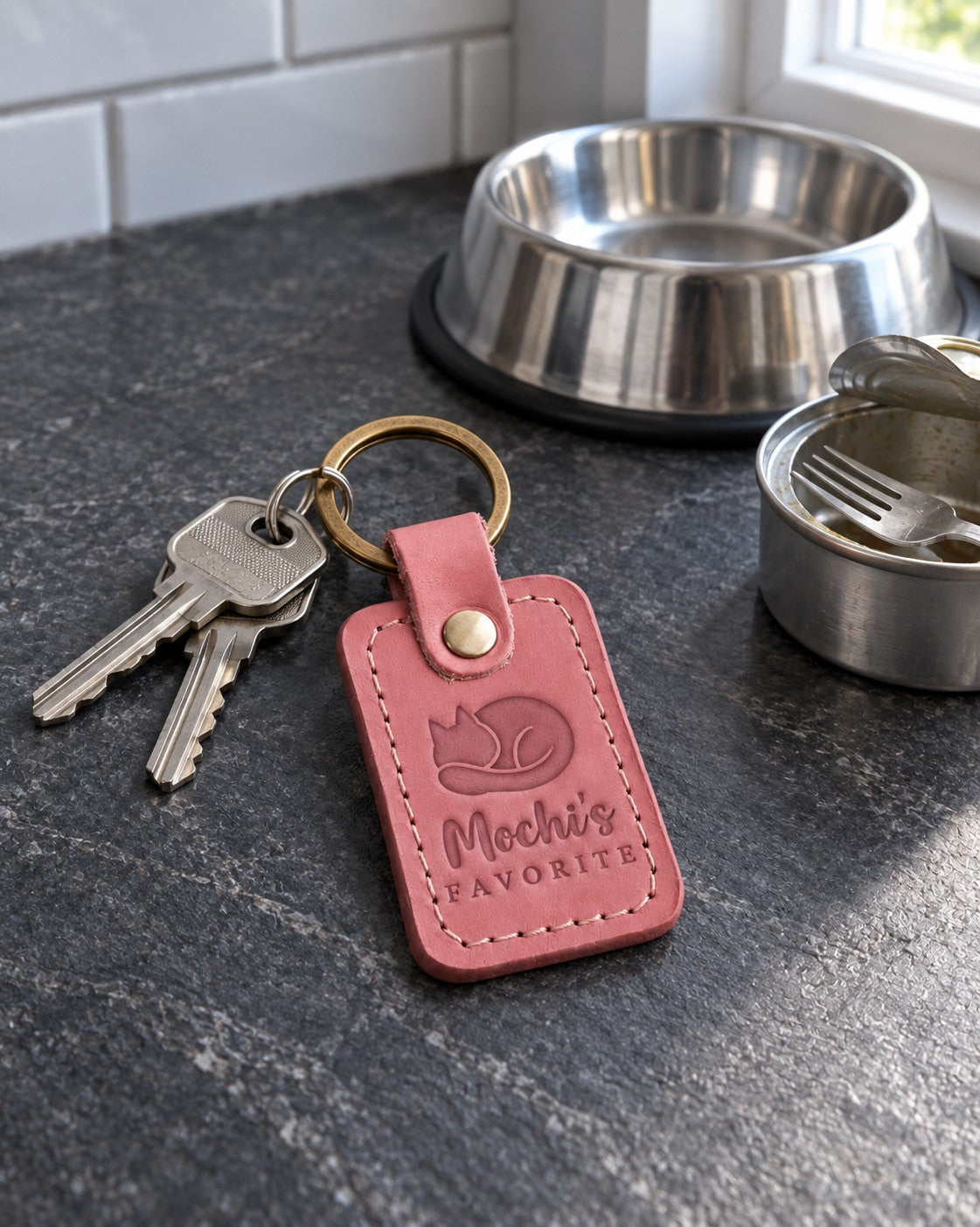 Mochi's FAVORITE keychain in rose pink leather on a knitted throw draped over a sofa