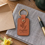 Caramel Daffodil March keychain beside a small vase of yellow daffodils on a kitchen table