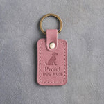 Parisian Blossom pink leather keychain debossed with a sitting dog above Proud and DOG MOM, on gray concrete