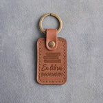 Caramel leather keychain debossed with a stack of books above Ex libris and BOOKWORM, on gray concrete