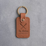 Caramel leather keychain debossed with two crossed bats above The Millers and GAME DAY, on gray plaster