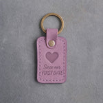 Lilac leather keychain debossed with a solid heart above the words Since our and FIRST DATE, on gray concrete