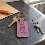 Lilac Grandma's House keychain on a front door key beside a wreath and a plate of cookies