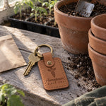 Caramel Homegrown Since keychain on a garden bench beside a bunch of freshly pulled carrots