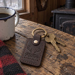 Miller Hunt Club keychain in dark brown leather on a gate padlock key at the entrance to a pine woods lease