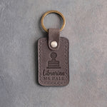 Country gray leather keychain debossed with a library date stamp above Librarian and MS HALE, on gray concrete