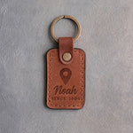 Sandy tan leather keychain debossed with a map pin above the name Noah and SINCE 2004, on gray concrete