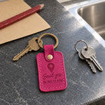Pink Said Yes coordinates keychain in an open gift box on a park bench beside a bouquet