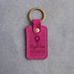 Fuchsia pink leather keychain debossed with a map pin above the words Right here and SHE SAID YES, on gray concrete
