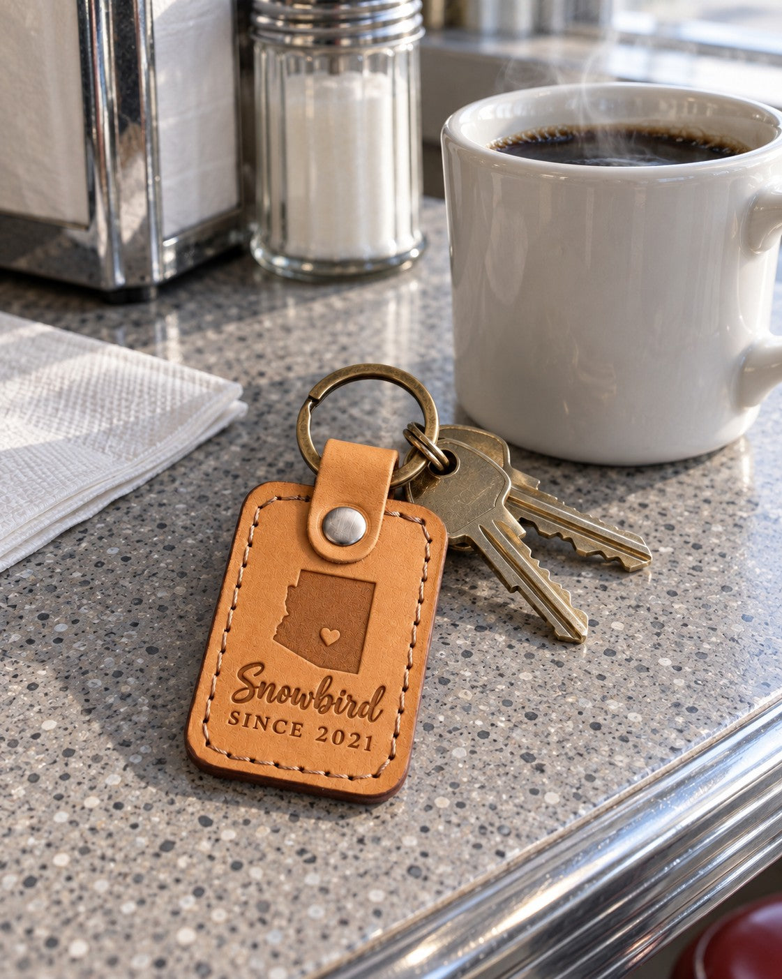Golden tan Snowbird keychain on condo keys resting on a patio table beside a potted cactus in winter sun