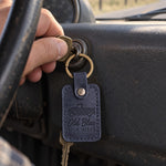 Navy Old Blue 300K MILES keychain hanging from the ignition of a well-used pickup