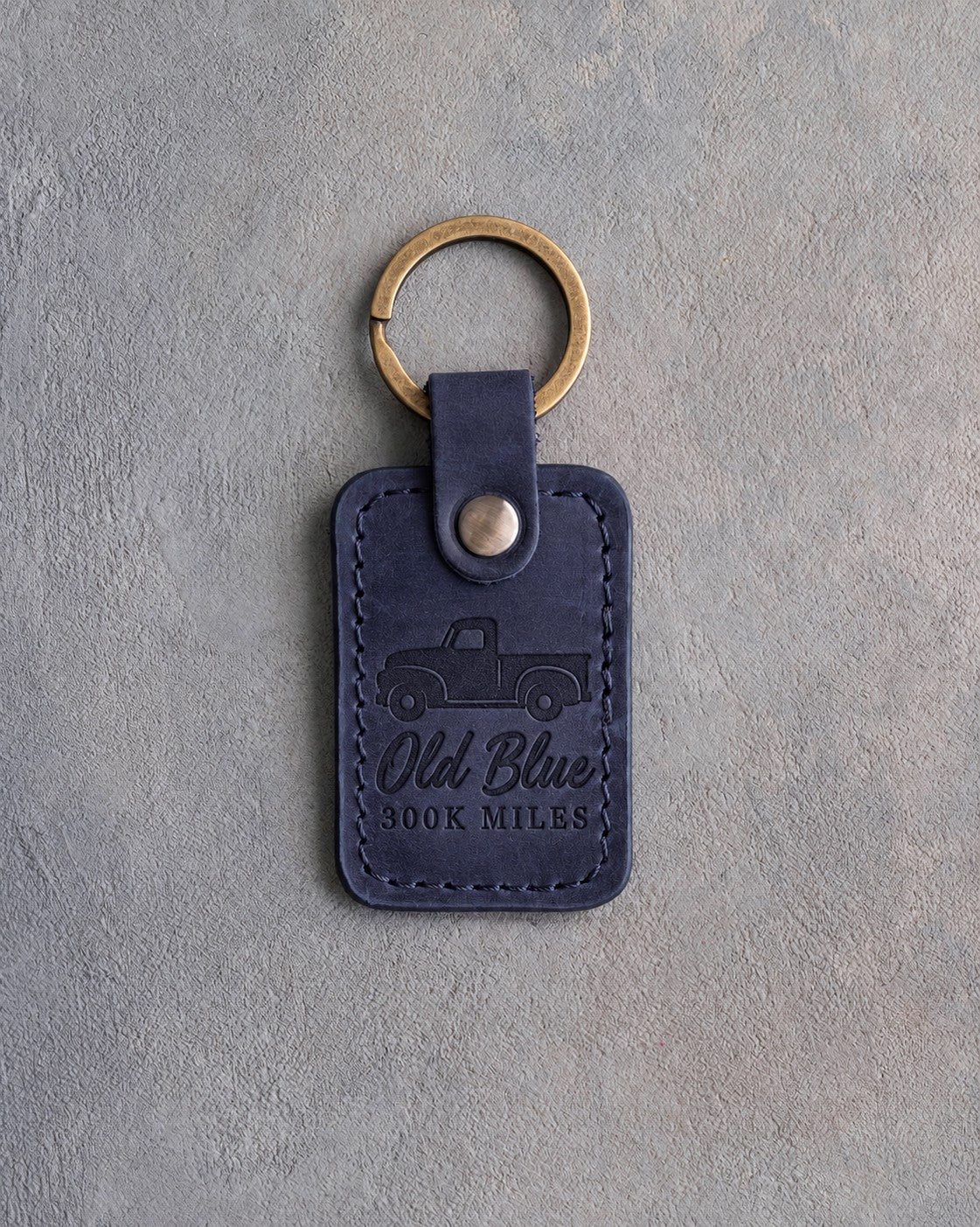 Blueberry navy leather keychain debossed with a classic pickup truck above Old Blue and 300K MILES
