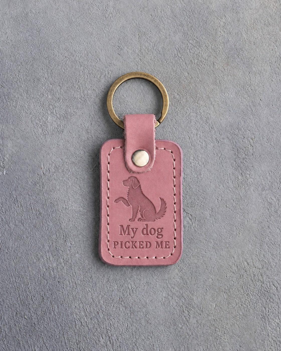 Parisian Blossom pink leather keychain debossed with a dog raising one paw above My dog and PICKED ME, on gray concrete