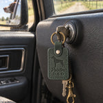 Forest green Pointer Dad leather keychain held in a warm everyday setting