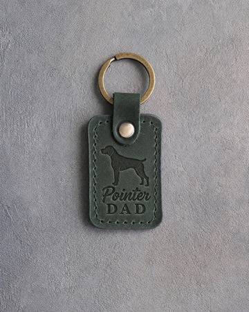 Forest green leather keychain debossed with a German Shorthaired Pointer silhouette and the words Pointer DAD, on gray concrete