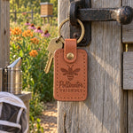 Caramel Pollinator Friendly keychain resting on a garden path beside purple coneflowers in summer light