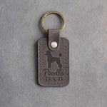 Country gray leather keychain debossed with a Poodle silhouette and the words Poodle DAD, on gray concrete