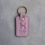 Lilac leather keychain debossed with a Poodle silhouette and the words Poodle MOM, on gray concrete